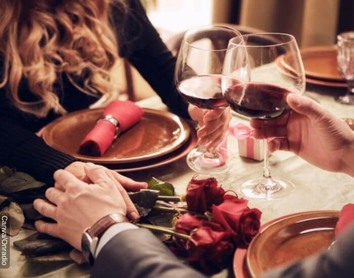 Foto de una cena romántica con rosas mientras toman vino y se agarran las manos representando lo que significa soñar con la persona que te gusta