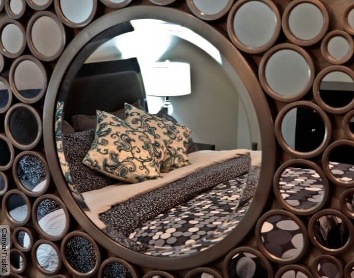 Foto de muchos espejos redondos juntos colgados en una pared reflejando la cama de la habitación