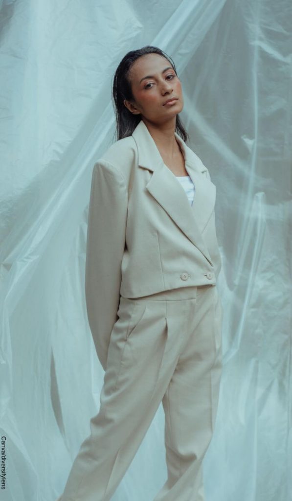 Foto de una mujer con traje de pantalón color crema mirando a la cámara
