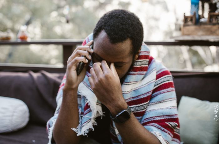 Foto de un hombre hablando por teléfono con una mano en la cara