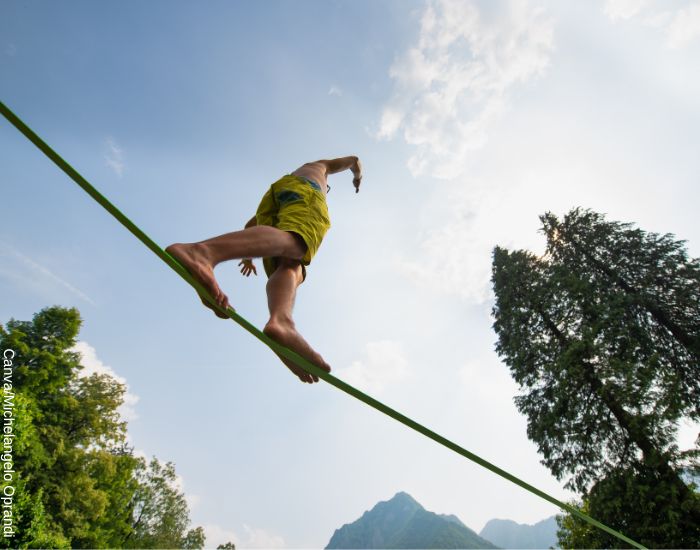 Foto de un hombre aventurero sin camisa caminando sobre una cuerda floja en medio de la naturaleza
