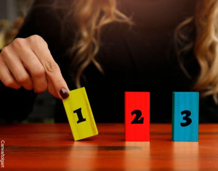 Foto de la mano de una mujer moviendo fichas con los números 1, 2 y 3