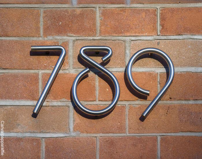 Foto de un aviso metálico en una pared de ladrillos con el número 789