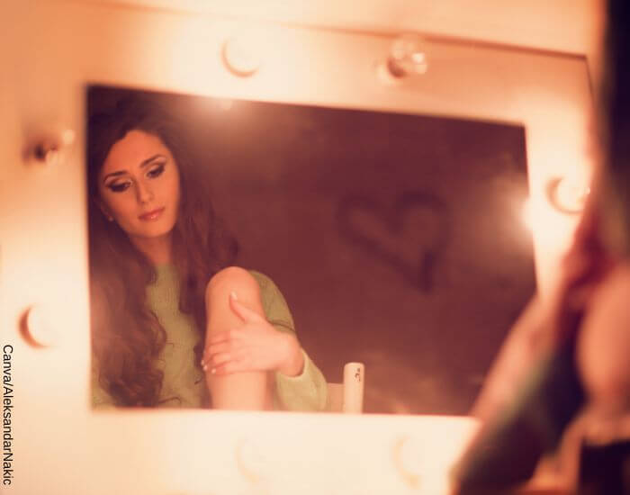 Foto de una mujer bonita mirando con tristeza el espejo con un corazón dibujado