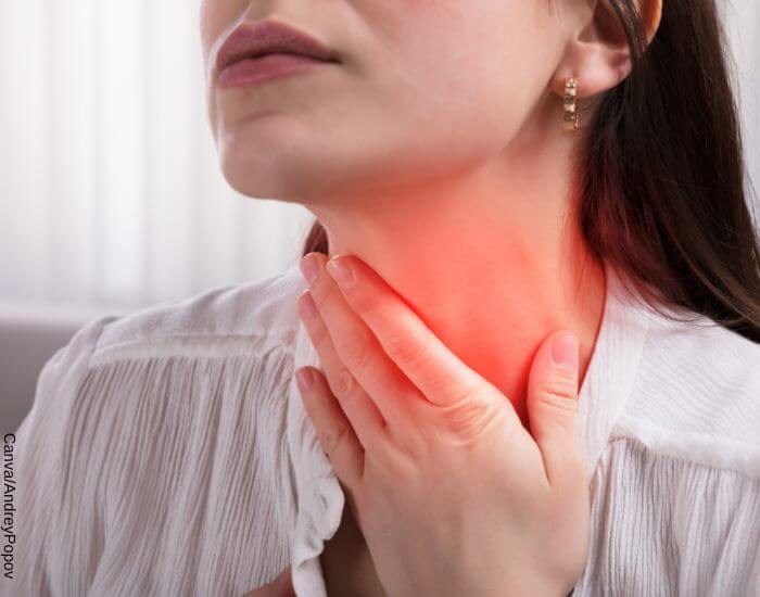 Foto de una mujer tocando su cuello en señal de dolor de garganta