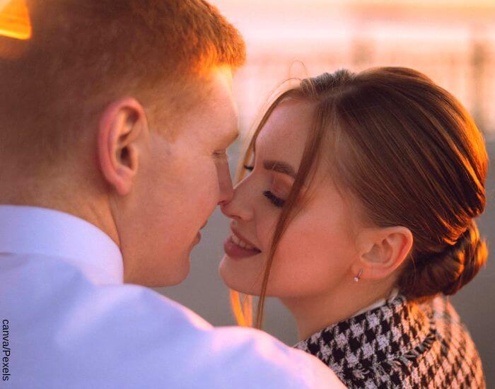 Foto de una pareja en un atardecer mirando sus labios a punto de besarse