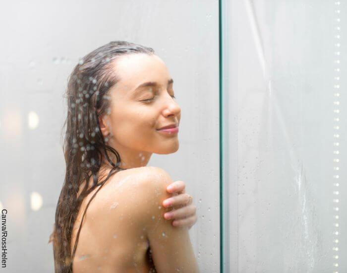 Foto de una mujer bajo la ducha con los ojos cerrados y una sonrisa