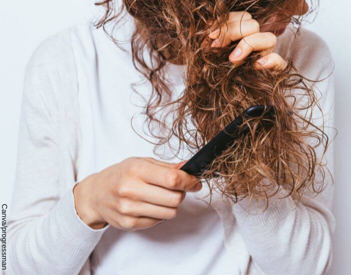 Foto de una mujer desenredando su cabello crespo con una peinilla