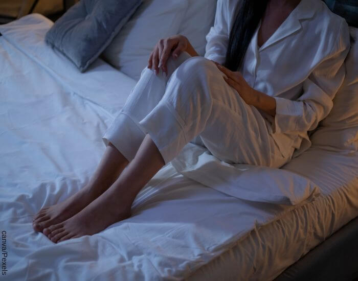 Foto de una mujer en pijama sobre su cama con sus pies descubiertos