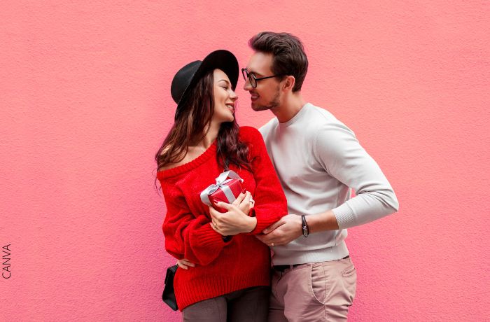 Foto de una pareja feliz y la mujer sosteniendo un regalo rojo