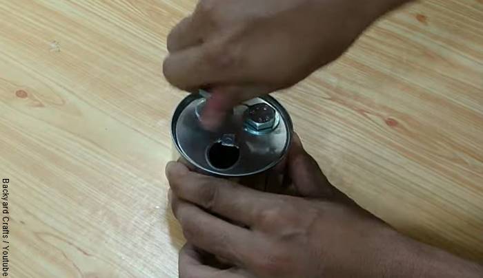 Foto de una lata a la que le están poniendo unos tornillos