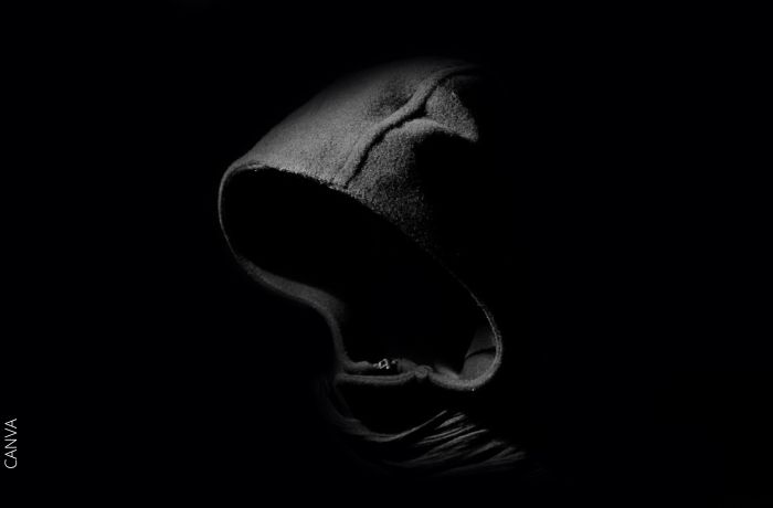 Foto a blanco y negro de una persona que esconde su rostro en su buzo