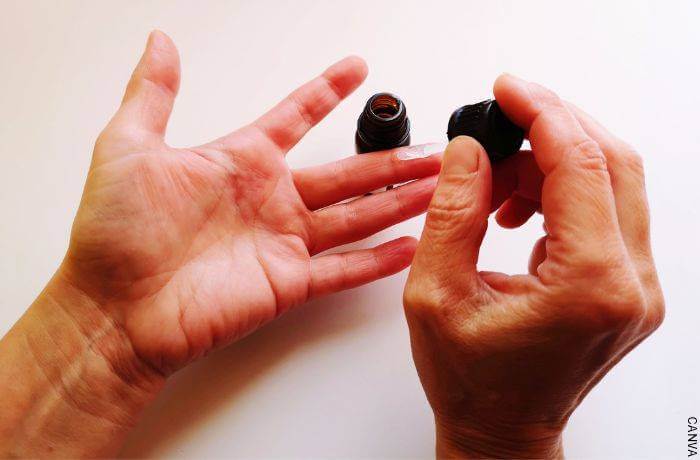 Foto de las manos de un hombre aplicándose un tratamiento en los dedos