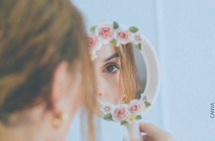 Foto de una mujer mirándose en un espejo pequeño de mano