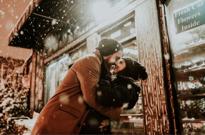 Foto de una pareja sonriendo bajo la nieve