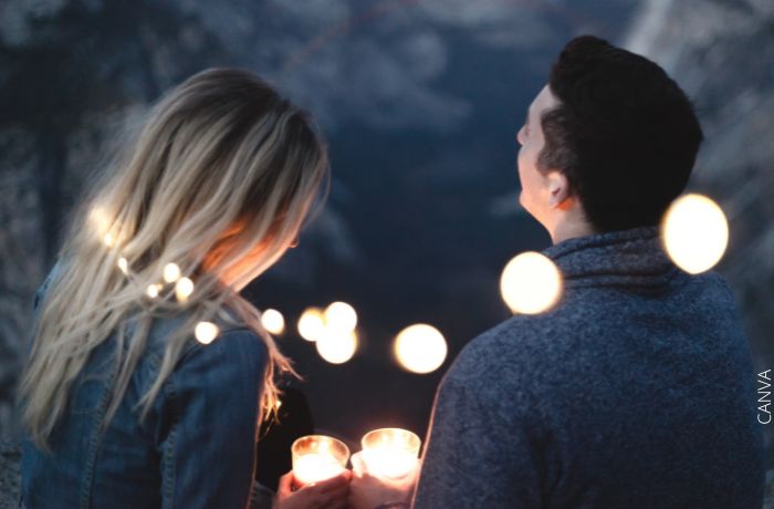 Foto de una pareja con velas en las manos y rodeados de luces