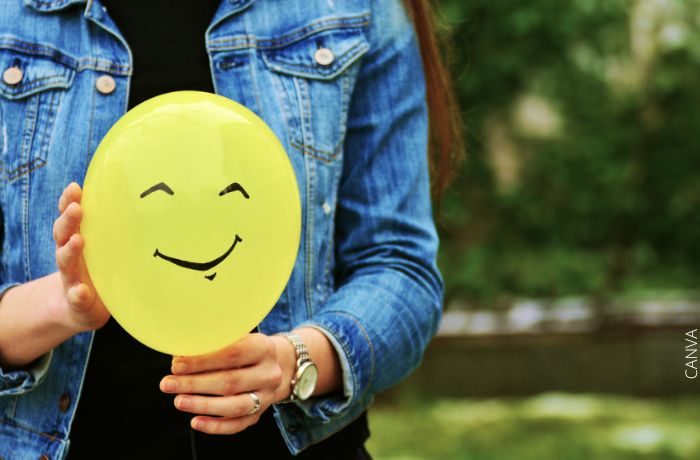 Foto de una mujer sosteniendo un globo amarillo con una cara feliz dibujada