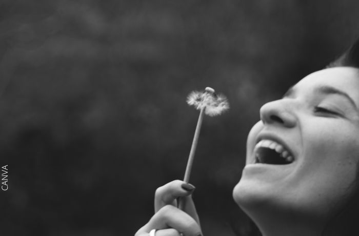 Foto a blanco y negro de una mujer feliz con una flor en la mano