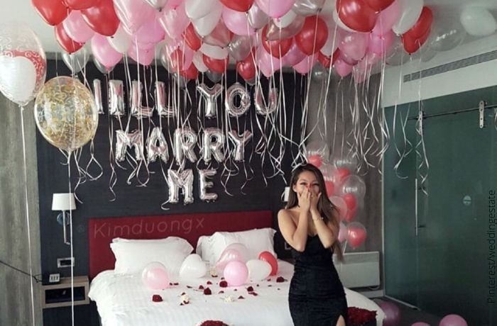 Foto de una mujer con una propuesta de matrimonio con globos