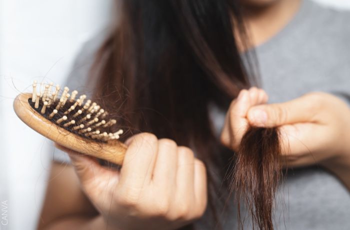 Foto de una mujer peinando su cabello y un cepillo en la mano