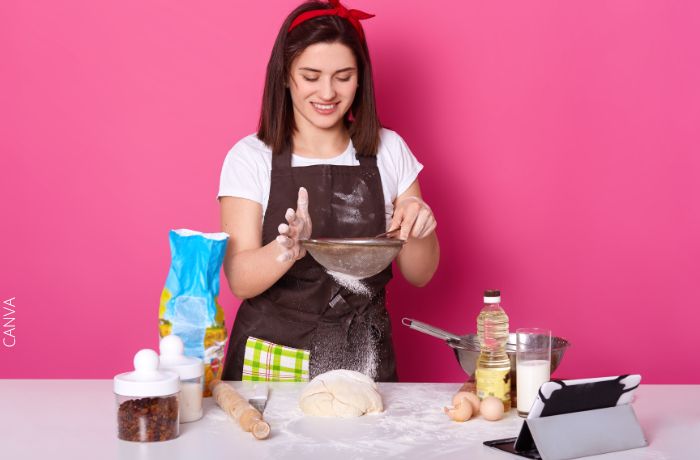 Foto de una mujer con delantal de cocina y preparando una maza de harina