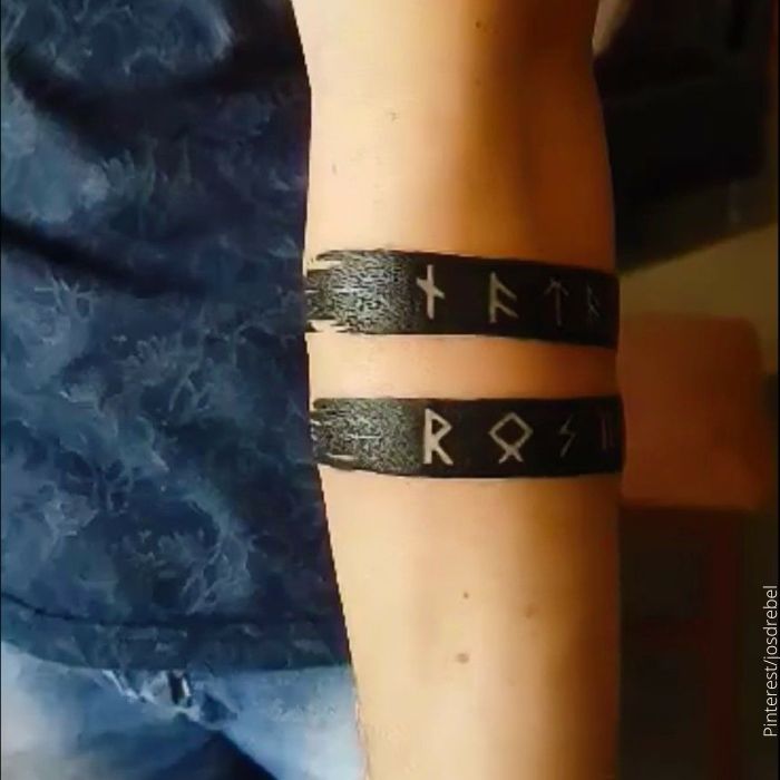 Foto de un tatuaje con forma de brazalete y runas vikingas