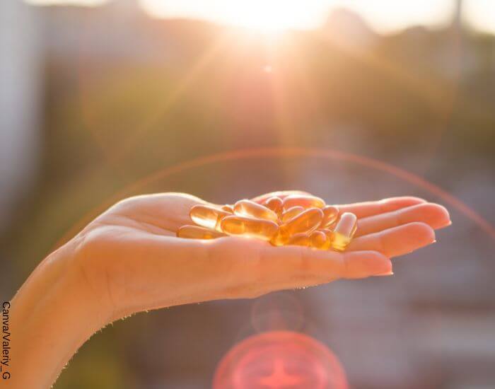 Foto de una mano sosteniendo varias cápsulas de omega 3 frente al horizonte
