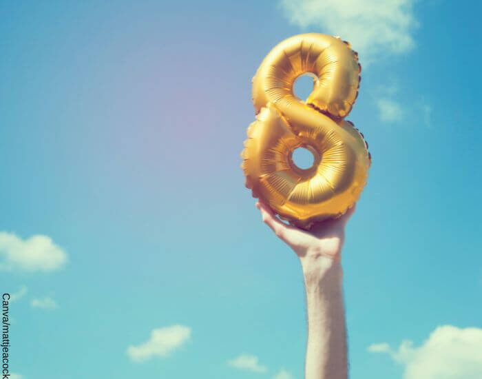Foto de una mano sosteniendo un globo dorado en forma de 8 en el aire como una de las supersticiones que atraen la buena suerte