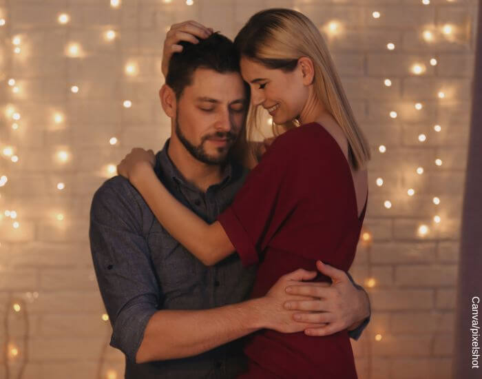 Foto de una pareja abrazados frente a las luces navideñas