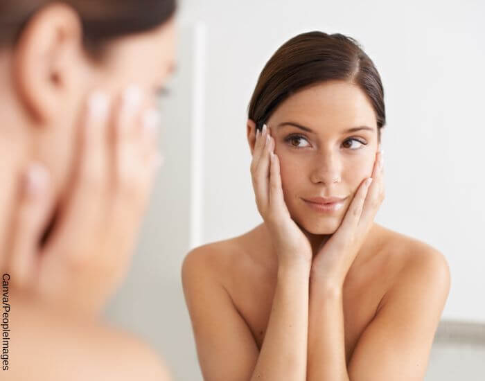 Foto de una mujer frente al espejo apreciando la suavidad de su rostro