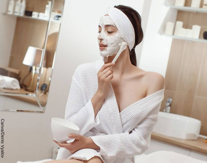 Foto de una mujer en el baño aplicando mascarilla en todo su rostro con una pala