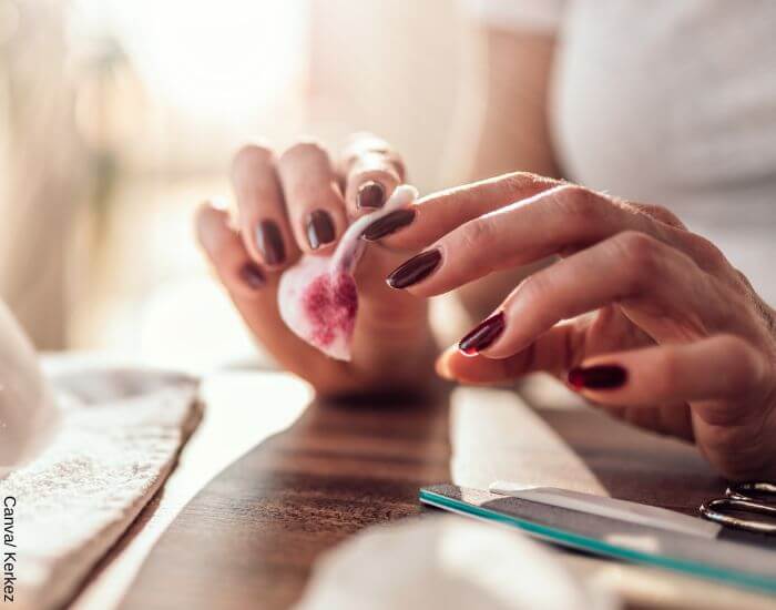 Foto de una persona quitando el esmalte de sus uñas con removedor