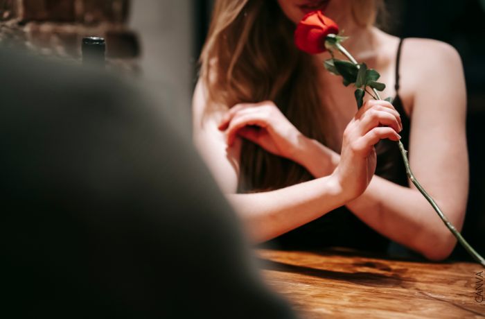 Foto de una mujer con una rosa mientras está con su pareja