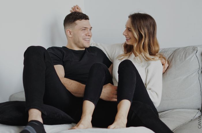Foto de una pareja riéndo sentados en la cama