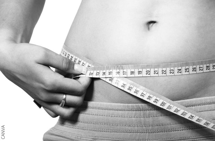 Foto de una persona midiendo su abdomen con una cinta métrica