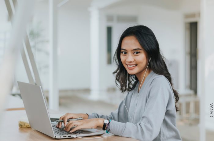 Foto de una mujer sonriendo mientras escribe en el computador