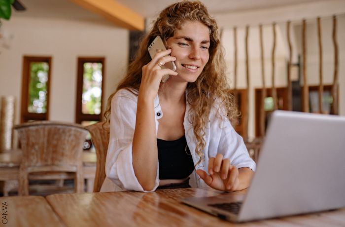 Foto de una mujer hablando por teléfono con el computador enfrente