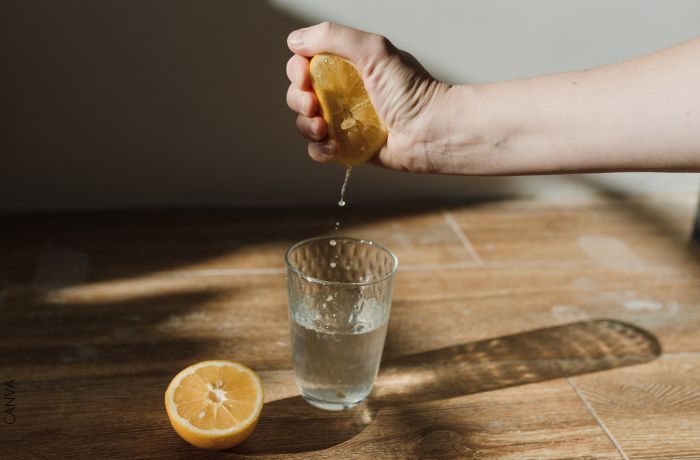 Foto de una persona exprimiendo un limón sobre un vaso de agua