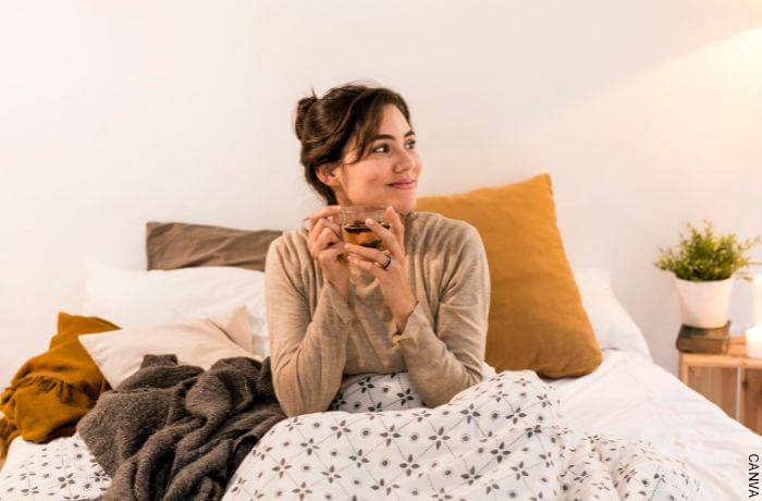 Foto de mujer tmando té en la cama