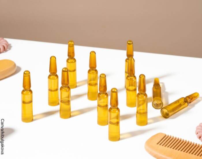 Foto de varias ampollas para el cabello sobre una mesa junto a cepillos