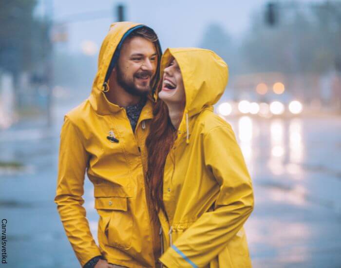 Foto de una pareja riéndo en medio de la lluvia en representación de cómo saber si un hombre está enamorado de ti