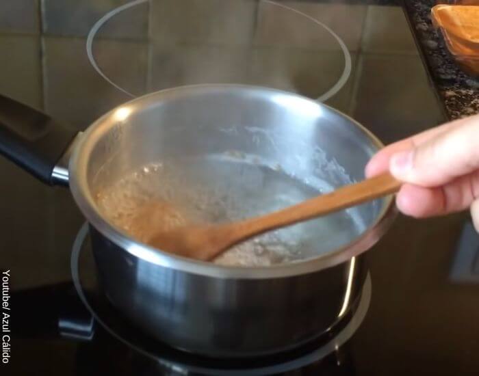 Foto de una olla con agua hirviendo y semillas de lino mientras es mezclada con una cuchara de palo