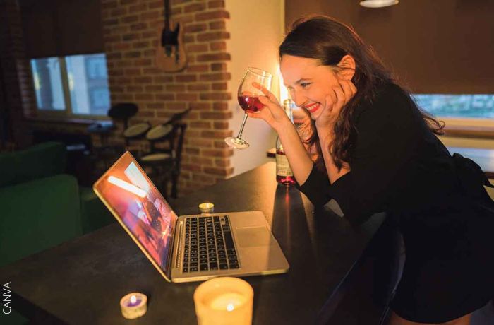 Foto de una mujer tomando vino mientras está en una videollamada