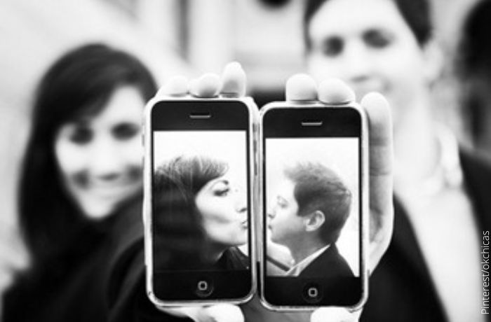 Foto a blanco y negro de dos personas sosteniendo los celulares simulando un beso