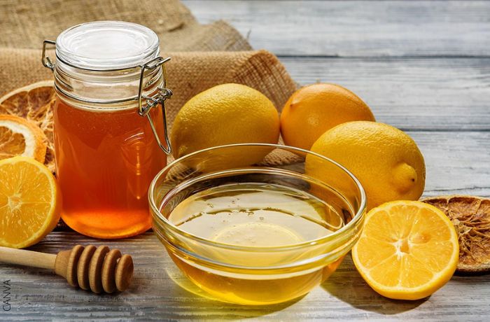 Foto de un frasco de miel y limones alrededor