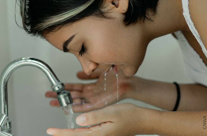 Foto de una mujer lavando su cara con agua