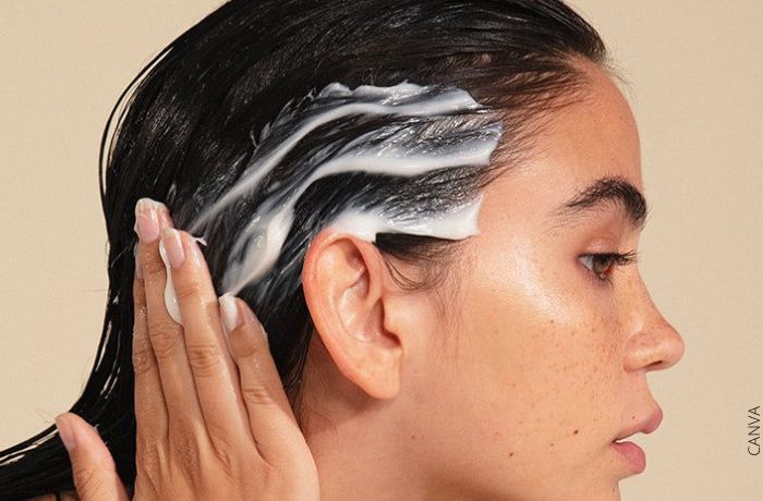 Foto de una mujer aplicandose un producto en el cabello