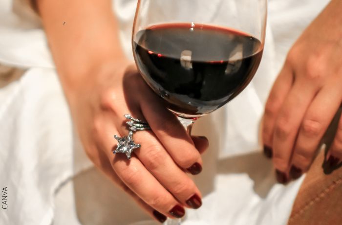 Foto de las manos de una mujer sosteniendo una copa de vino