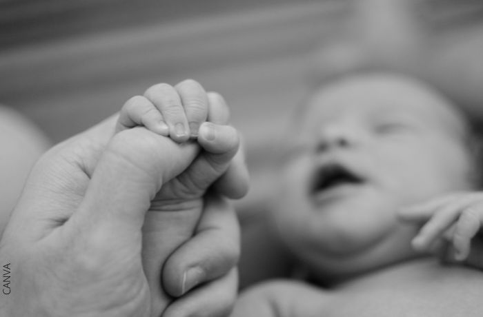 Foto a blanco y negro de un persona sosteniendo la mano de un bebé