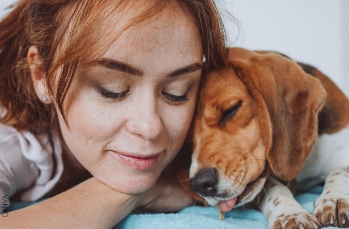 Foto de una mujer durmiendo con la cabeza junto a la de su perro